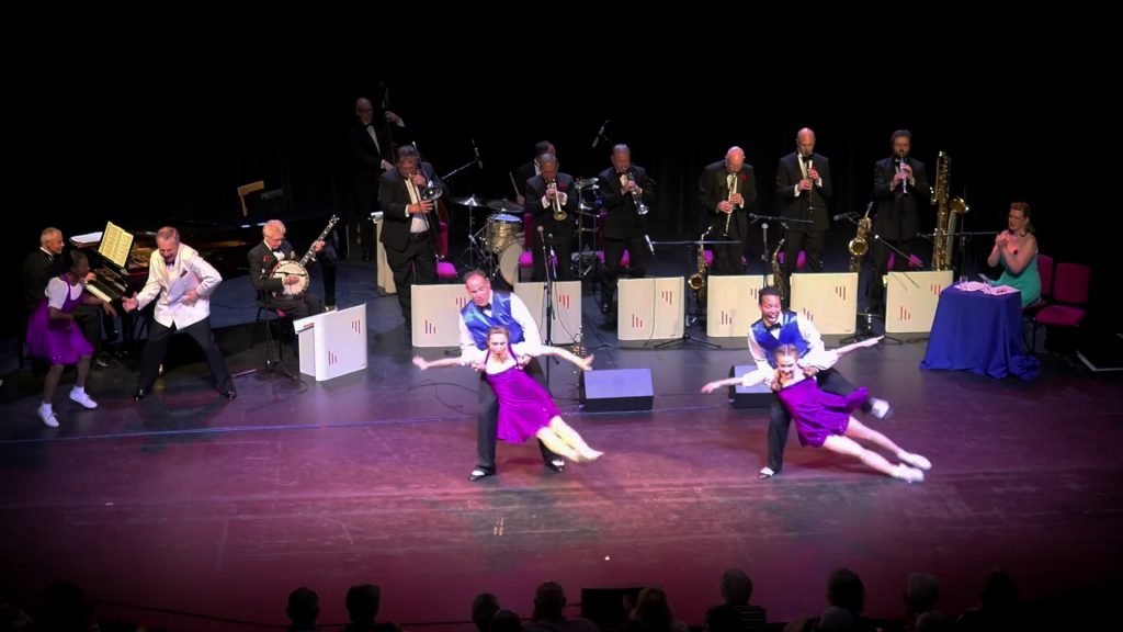 Picture of the TJO Dancers with the orchestra in the background